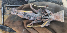 Bronzefigur Vogelmann mit Eingusstrichter und Abluftkanälen (gelblich)